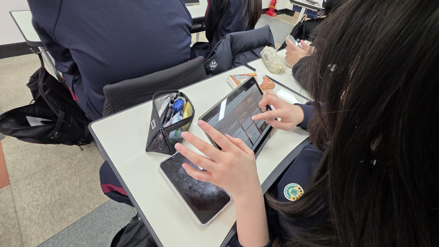 태블릿 화면을 통해 생성형 AI의 결과물을 검토하고 개선해 나가는 학생의 디테일한 손놀림이 포착되었습니다.