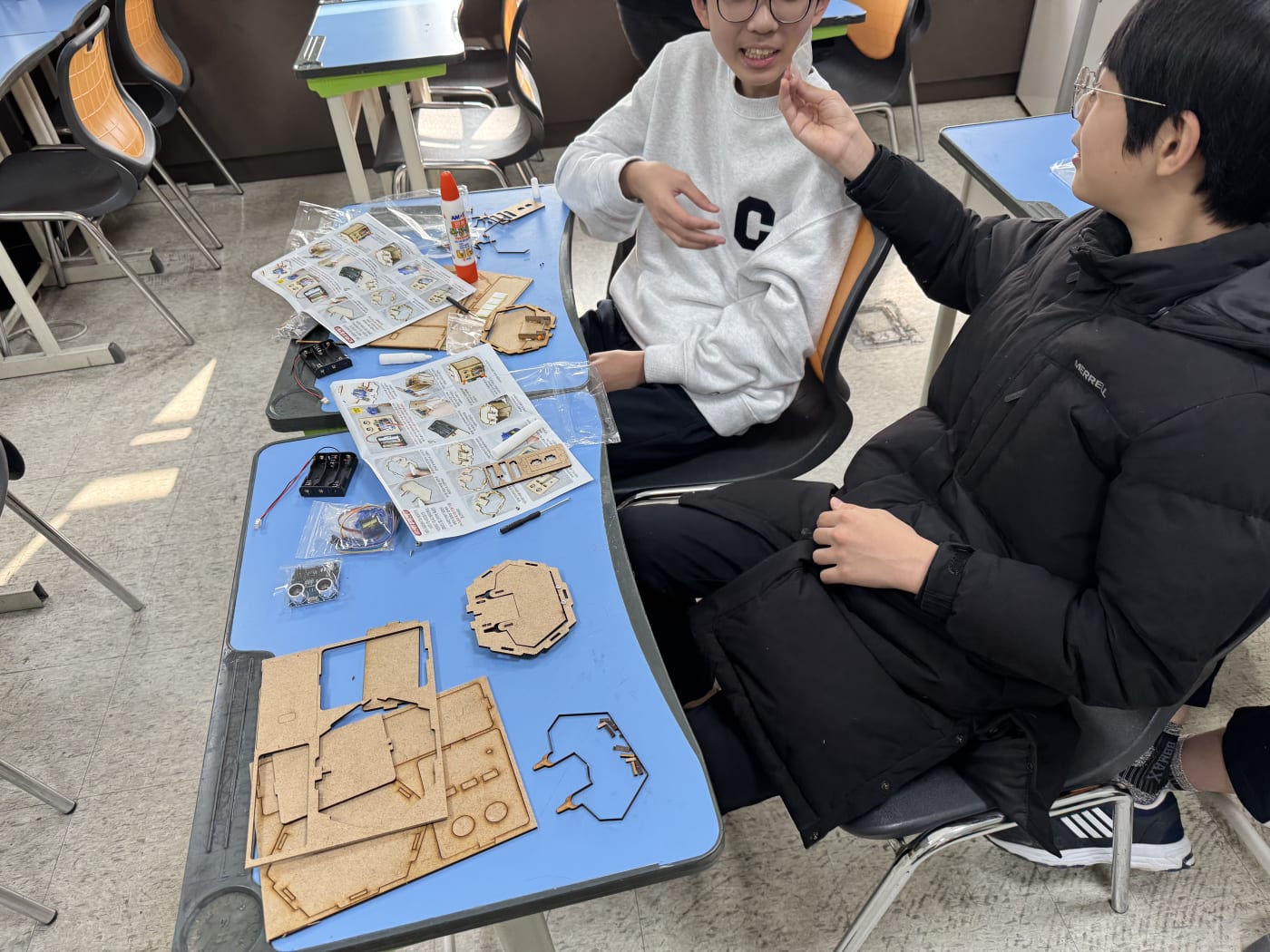 친구와 함께 완성된 로봇 휴지통을 보며 환하게 웃고 있는 학생