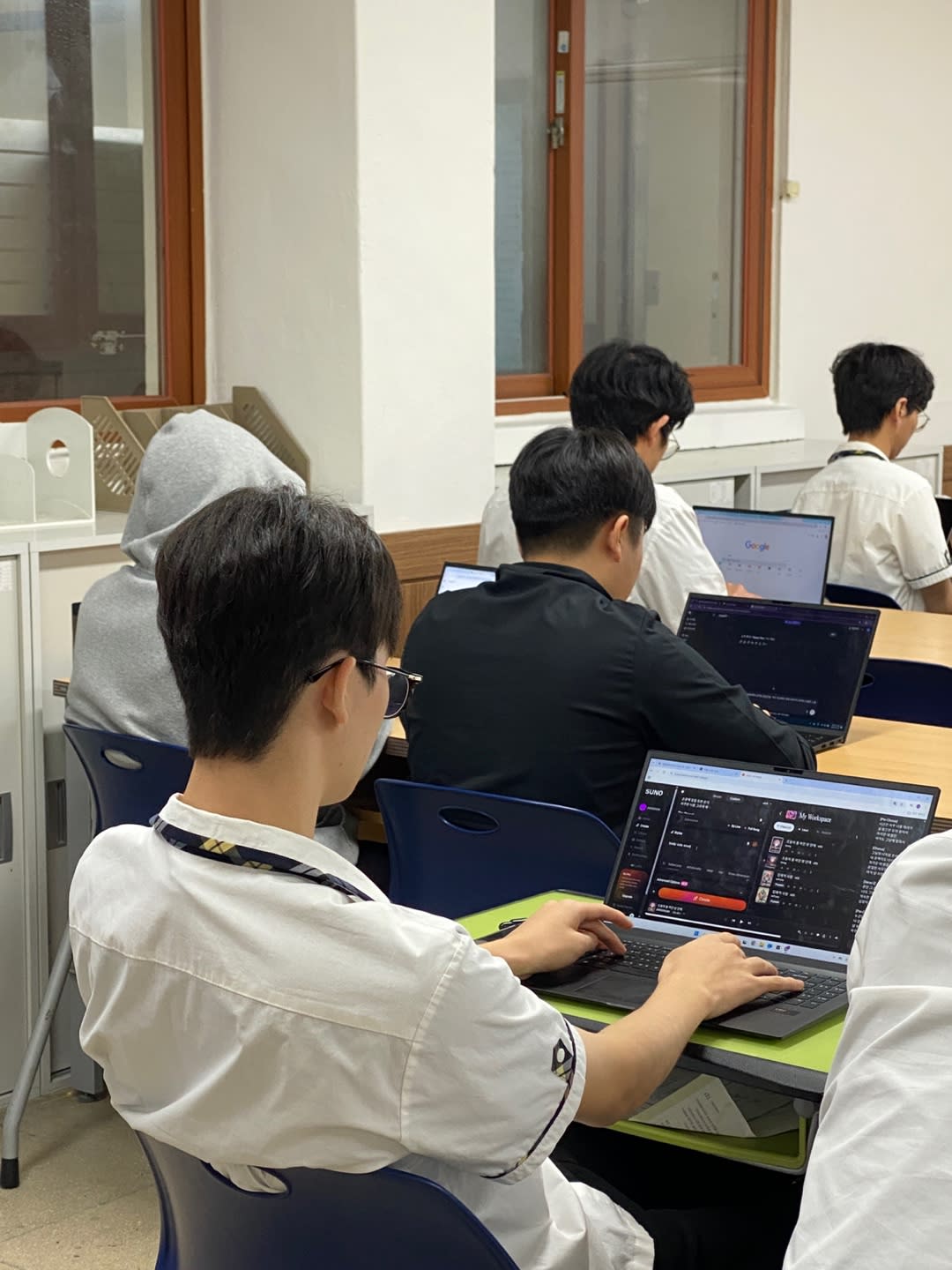 학생들이 각자 노트북을 활용해 코드 에디터에 집중하고 있는 모습입니다. 고도의 집중력이 발휘되는 현대적인 학습 환경을 묘사하고 있습니다.