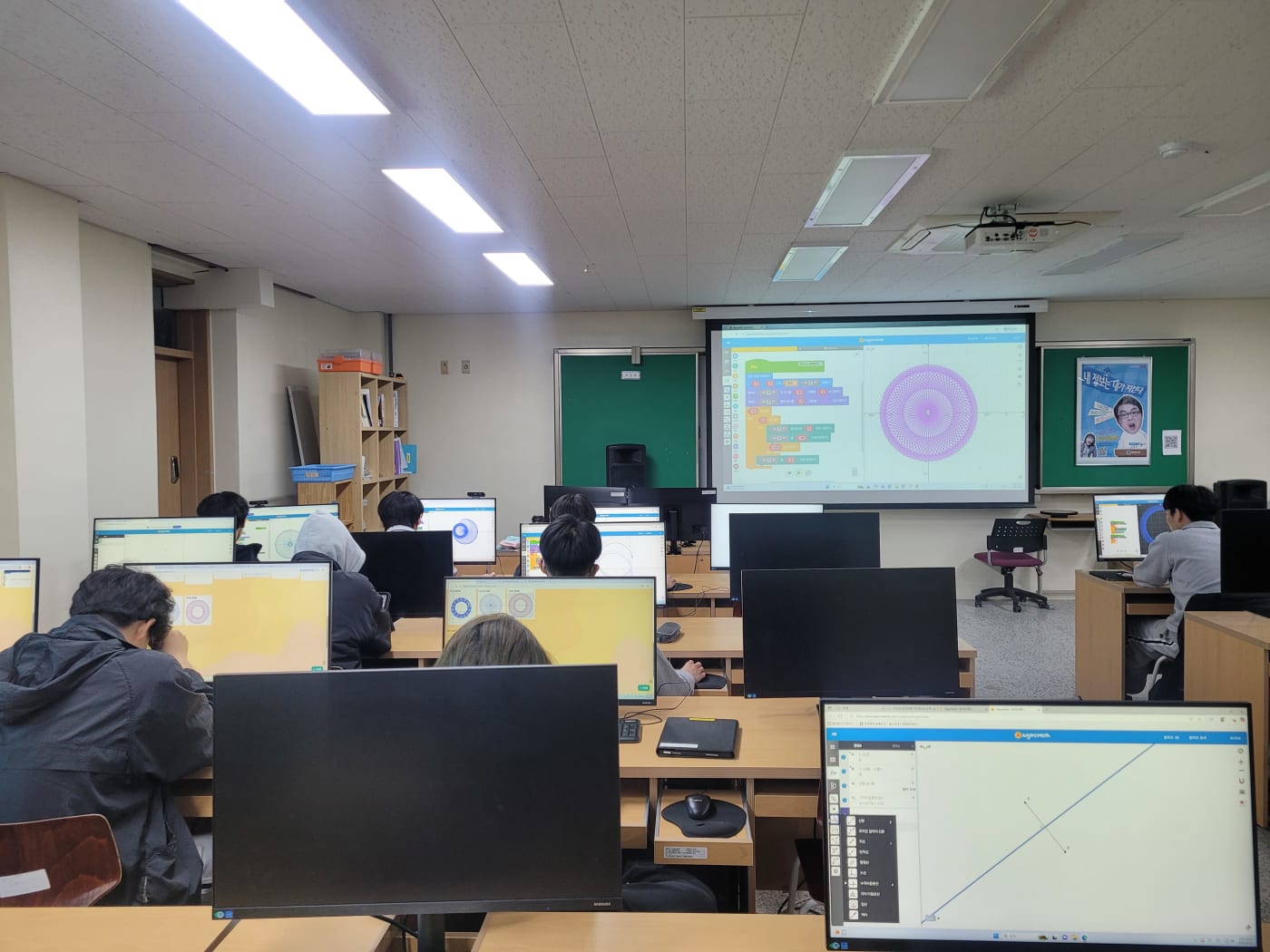 컴퓨터실 전체가 알지오매스와 바이브코딩을 활용한 열띤 탐구의 장으로 변모한 모습입니다. 학생들의 화면마다 펼쳐진 고유의 수학 세계가 인상적입니다.