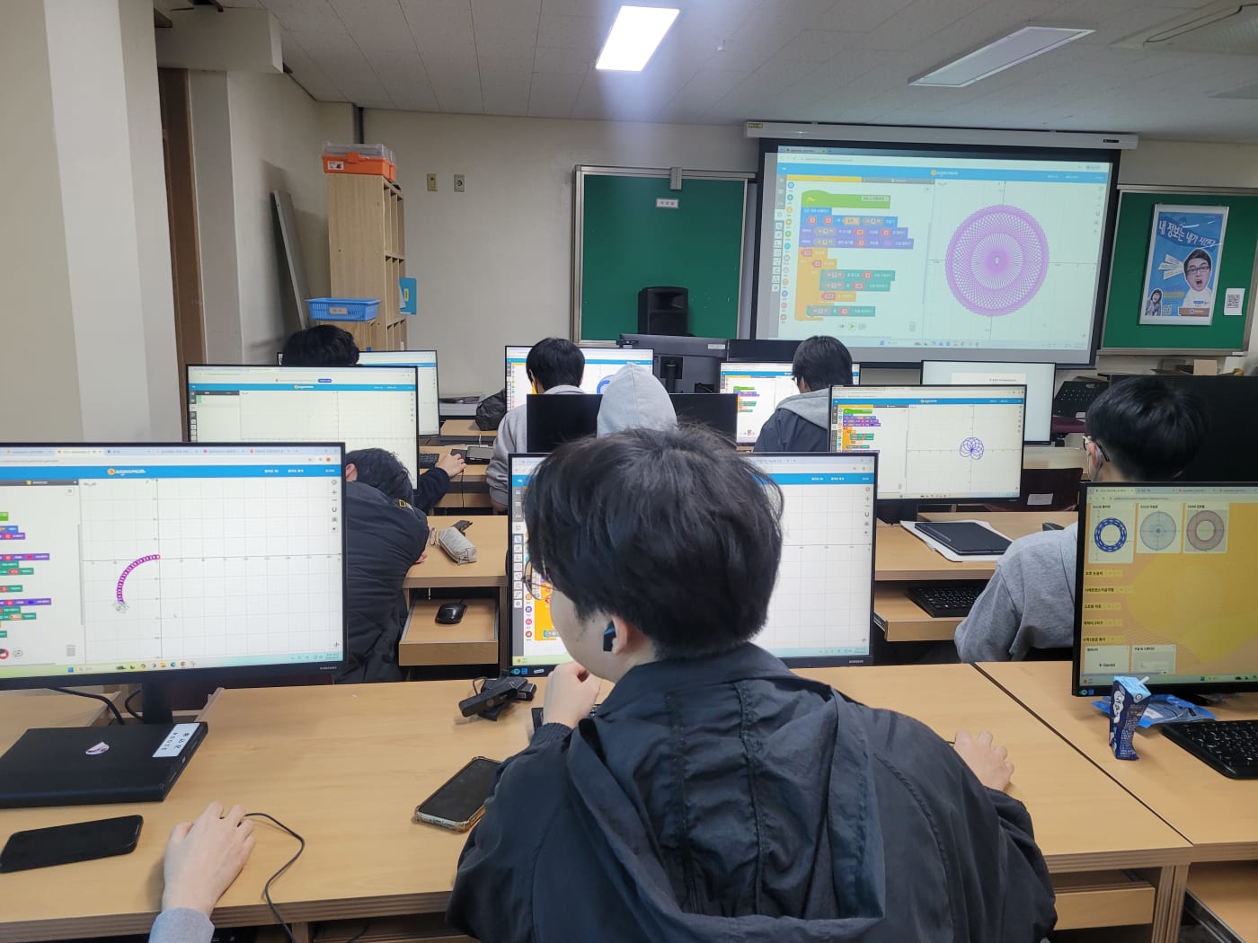 바이브코딩 인터페이스를 통해 수학 튜터 웹앱의 로직을 구성하는 학생들의 뒷모습에서 전문 개발자 못지않은 진지함이 느껴집니다. 수학과 정보가 결합된 융합 수업의 전형입니다.