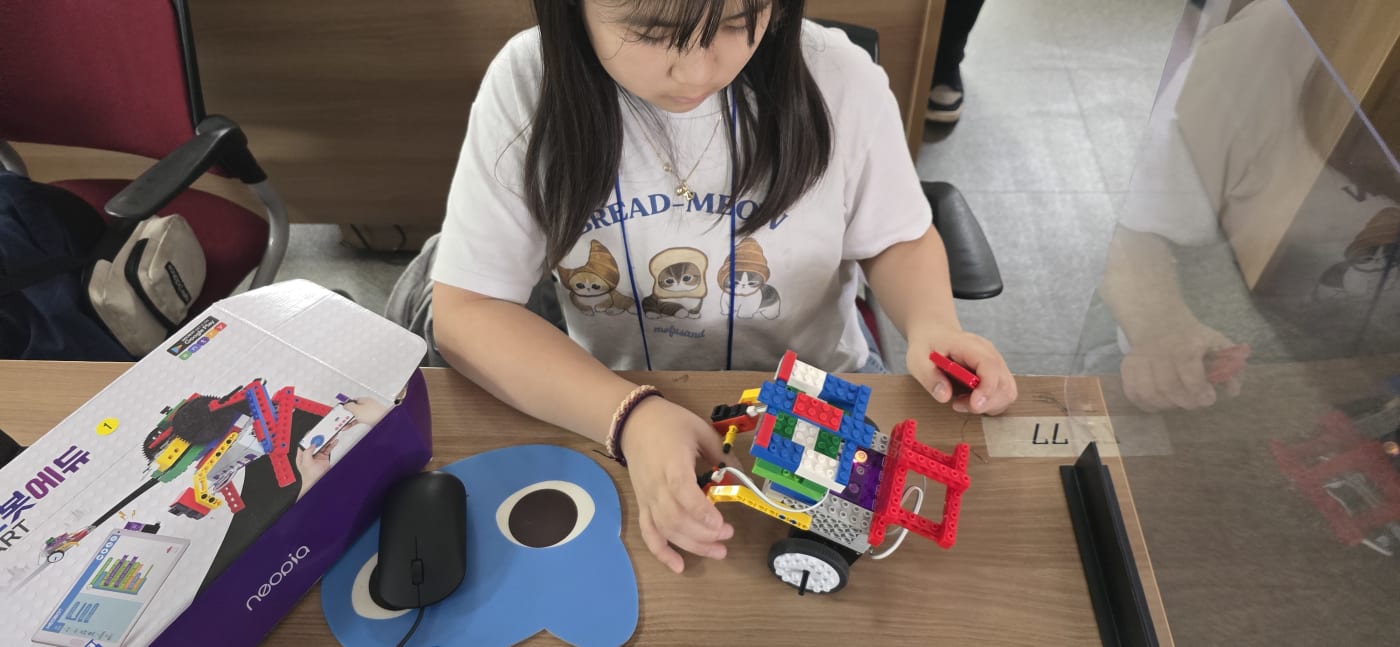알록달록한 블록을 조합하여 자신만의 독특한 자율주행 자동차를 설계하고 있는 학생의 모습입니다.
