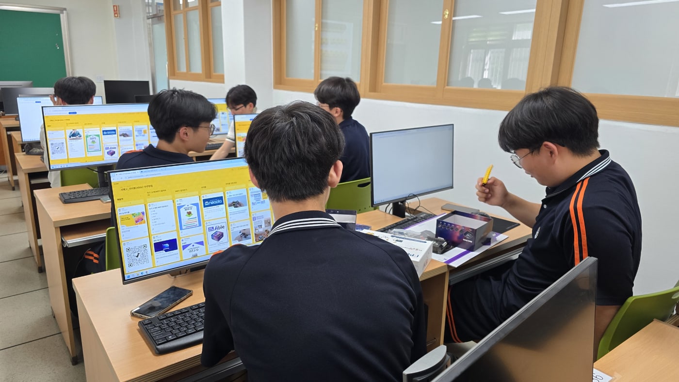 패들렛에 올라온 창의적인 아이디어들을 보며 학생들이 밝게 미소 짓고 있다.