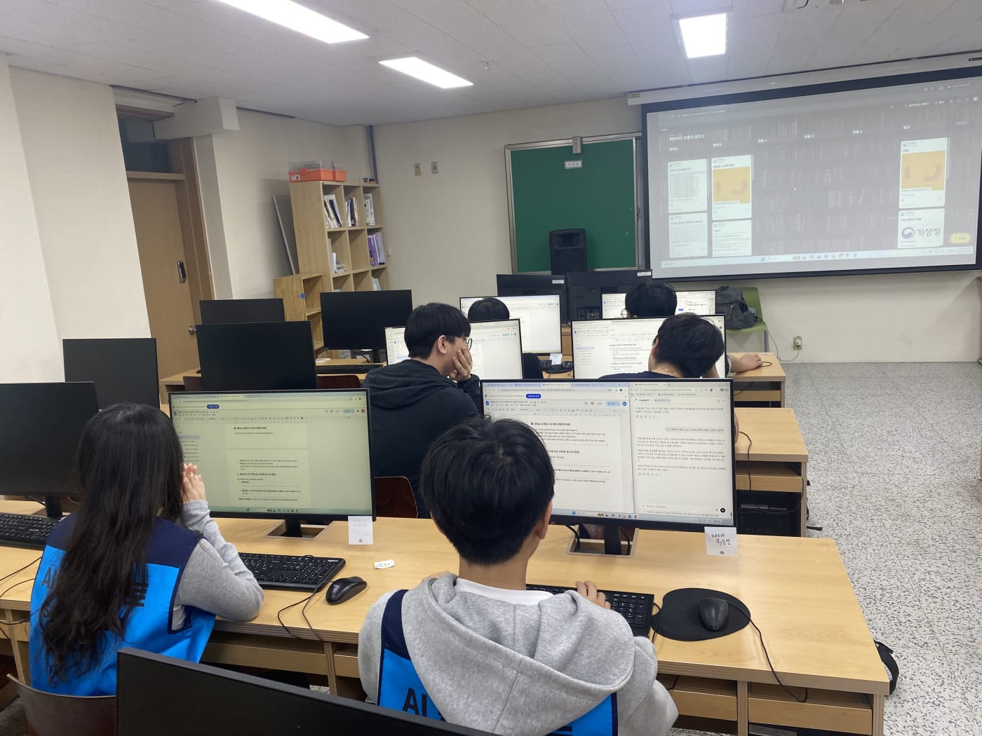 멘토와 학생들이 함께 기상청 데이터를 분석하며 선형회귀모델의 정확도에 대해 토론하고 있다.