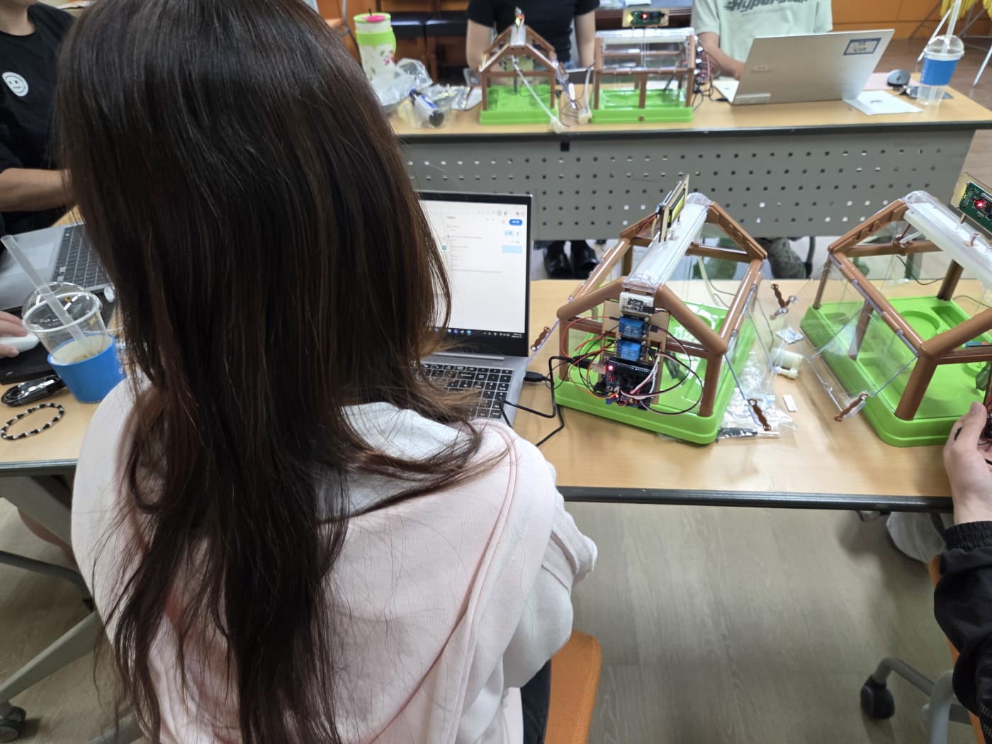 완성된 스마트팜 키트와 노트북을 연결하여 시스템을 테스트하는 장면으로, 기술과 농업의 결합을 시각적으로 보여줍니다.