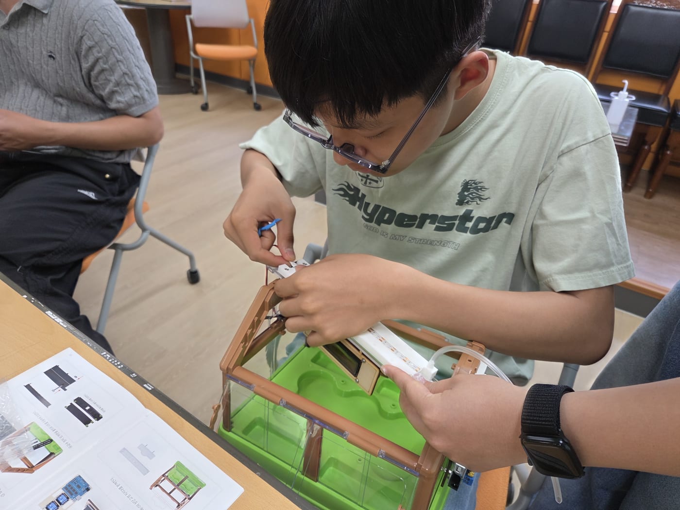 온실 상단에 LED와 호스를 꼼꼼하게 부착하며 스마트팜의 핵심 기능을 구현하는 세밀한 과정입니다.