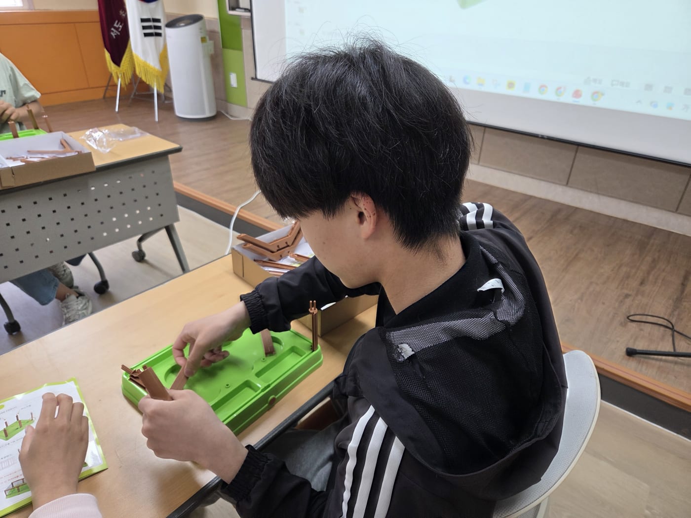 조립 매뉴얼을 곁에 두고 꼼꼼하게 부품을 조립하는 학생의 모습으로, 교육 프로그램의 체계성을 보여줍니다.