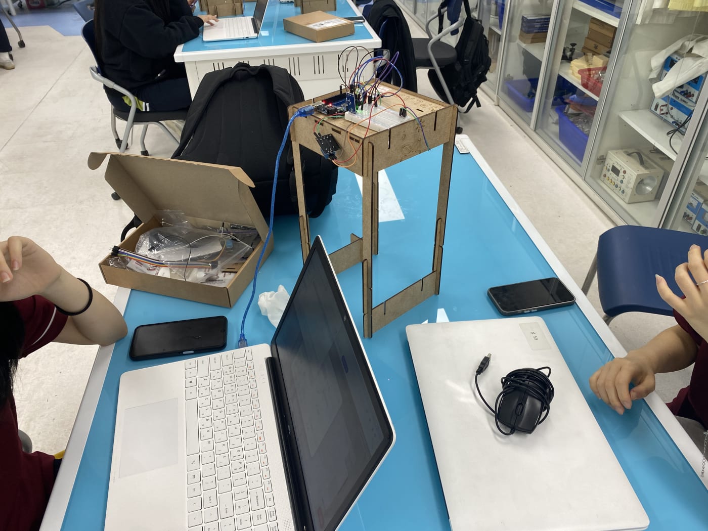 실습 테이블 위에 펼쳐진 노트북과 복잡하게 연결된 센서 회로를 통해 이론이 실제로 구현되는 역동적인 메이커 교육의 과정을 묘사합니다.