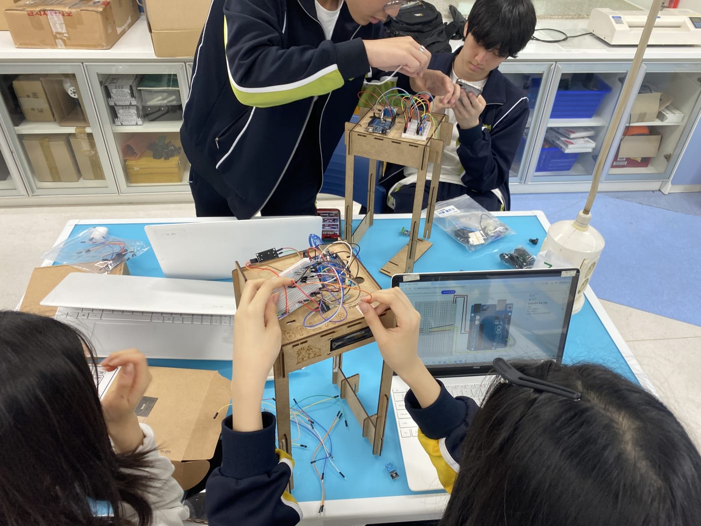 친구들과 머리를 맞대고 노트북 회로도를 보며 스마트팜 회로를 구성하는 학생들.