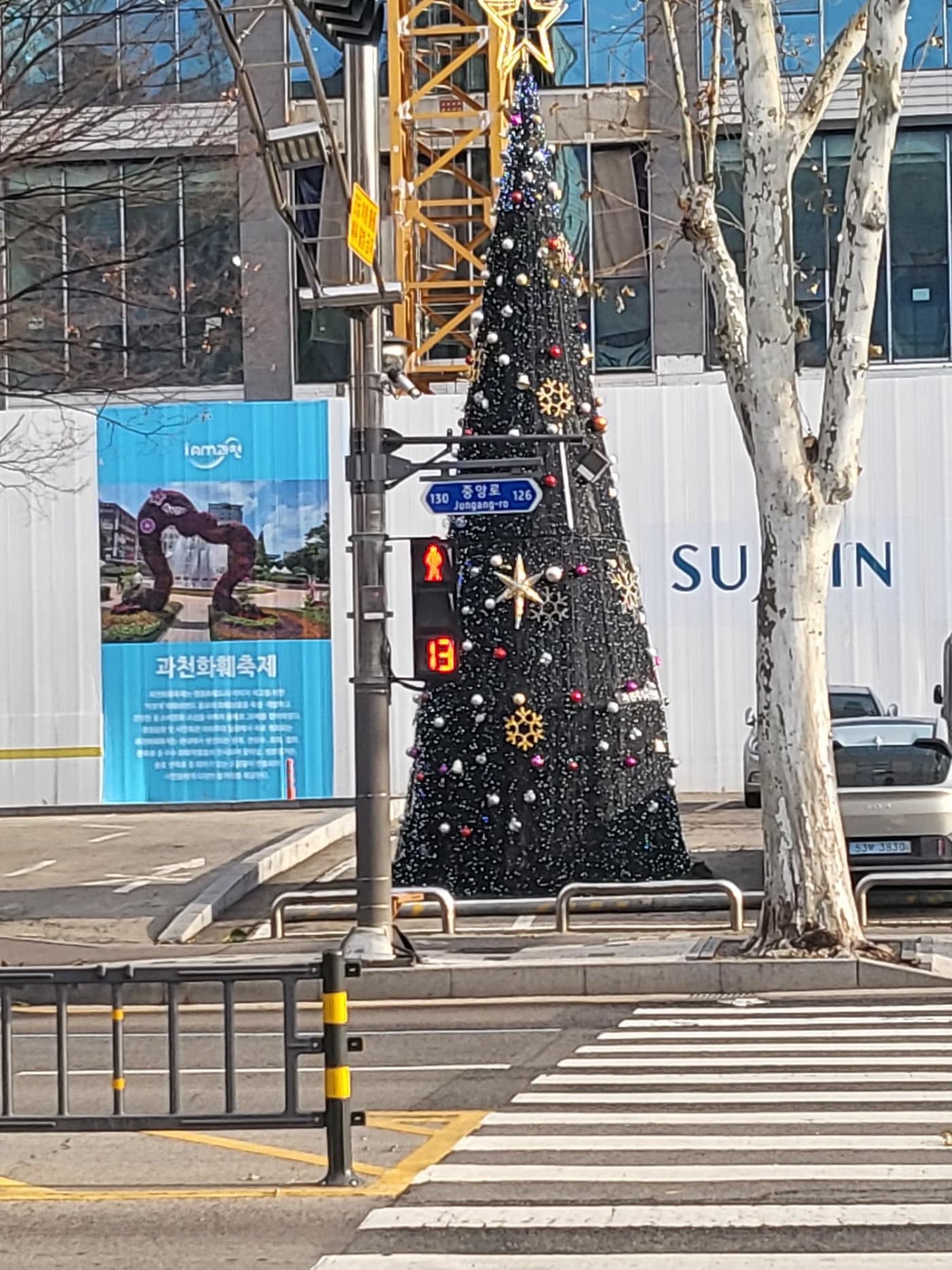 연말 분위기의 대형 트리 장식과 어우러진 횡단보도 풍경입니다. 13초라는 구체적인 적색 잔여 시간이 보행자에게 정확한 정보를 제공하며, 유동인구가 많은 상업 지구에서도 질서 정연한 대기 환경을 조성하고 있습니다.