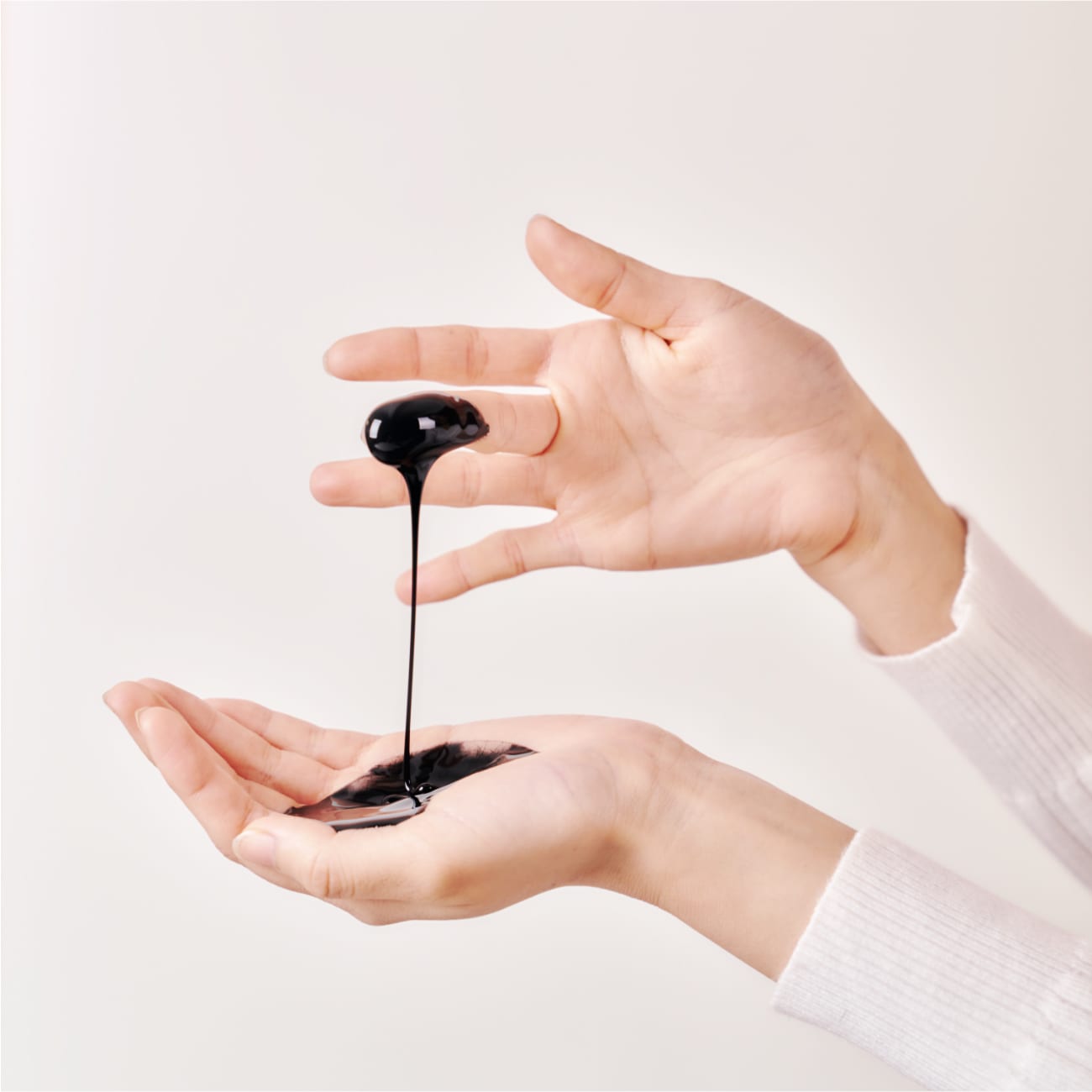 Black highly concentrated essence flowing over a hand
