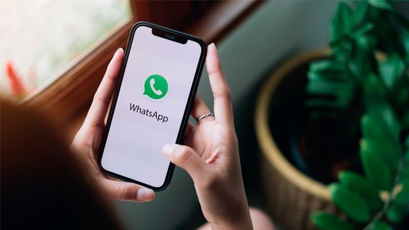 Ilustração de um celular com a logo do WhatsApp e vários balões de conversa