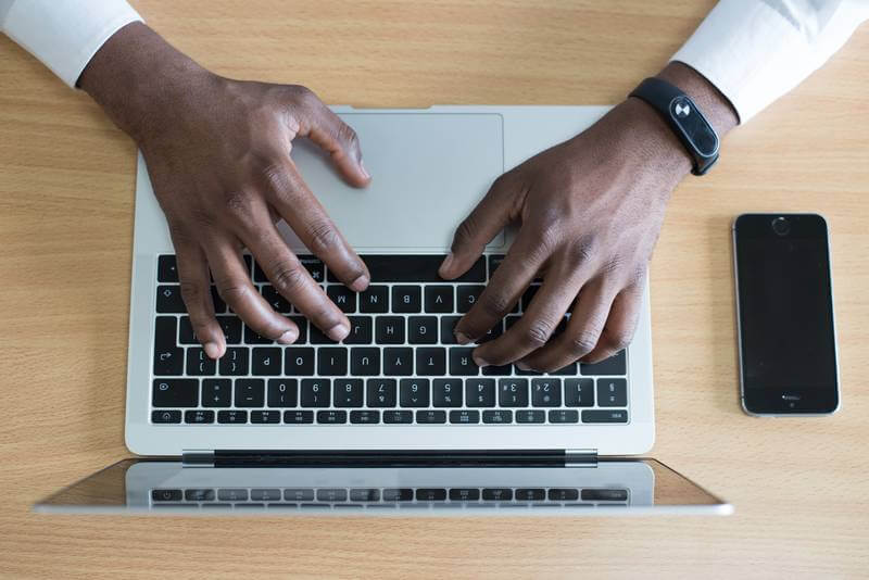 The image shows someone typing on a notebook