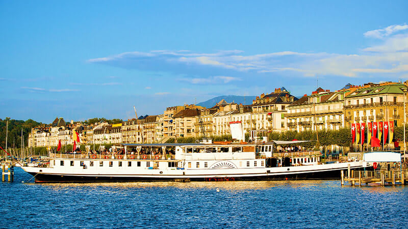 imagem panorâmica de Lausanne - Suiça mostrando o contraste entre a cidade e os alpes, com um lago separando os dois