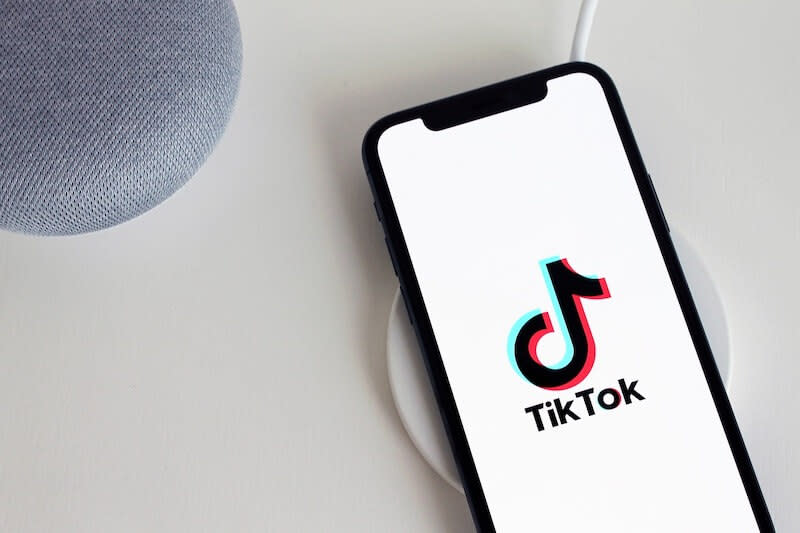 The image shows a smartphone with the TikTok logo on the screen