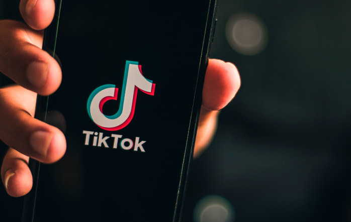 Foto de uma pessoa segurando um celular com a logo do TikTok