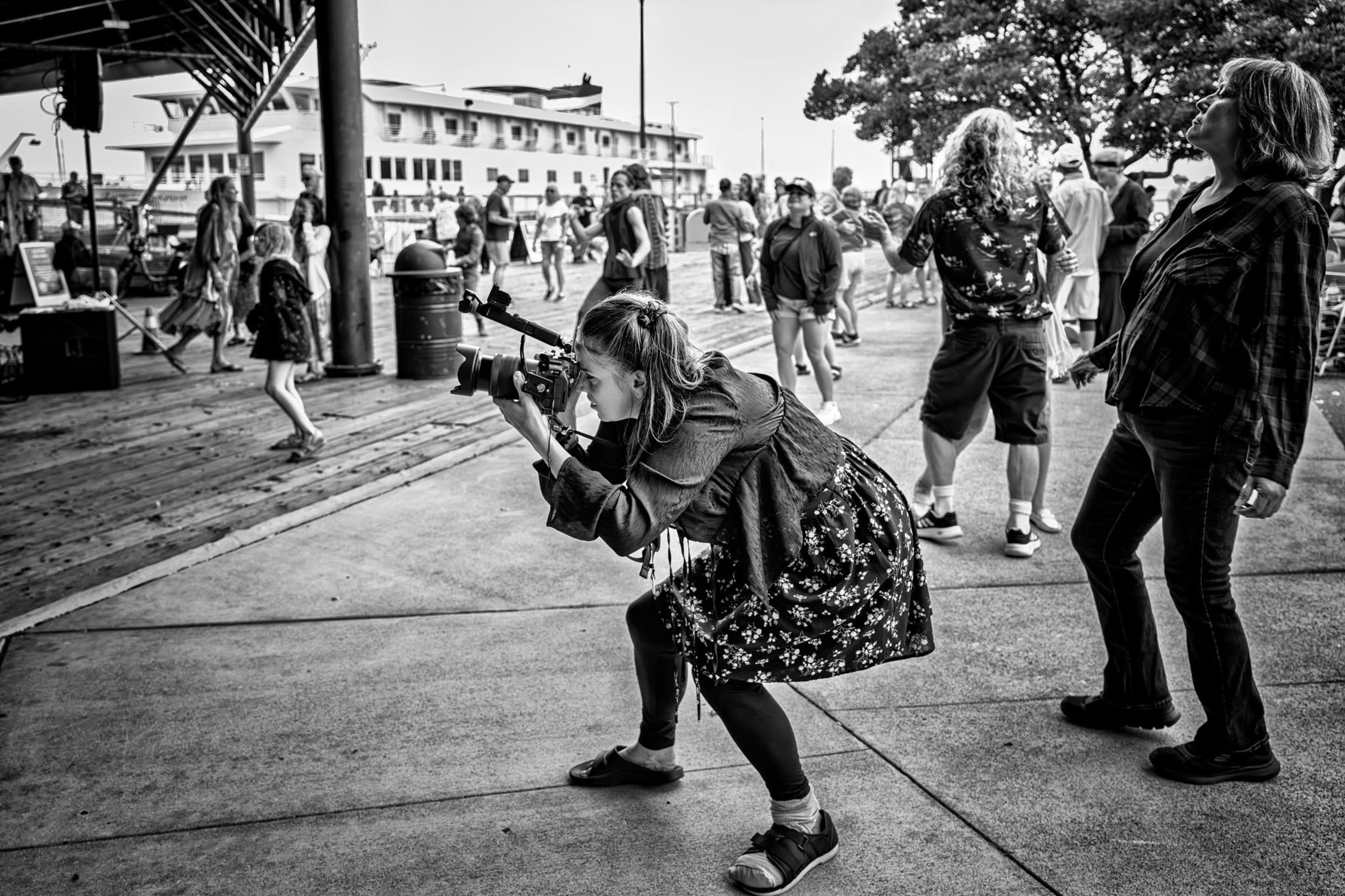 Alaina crouched shooting a crowd session on a pier