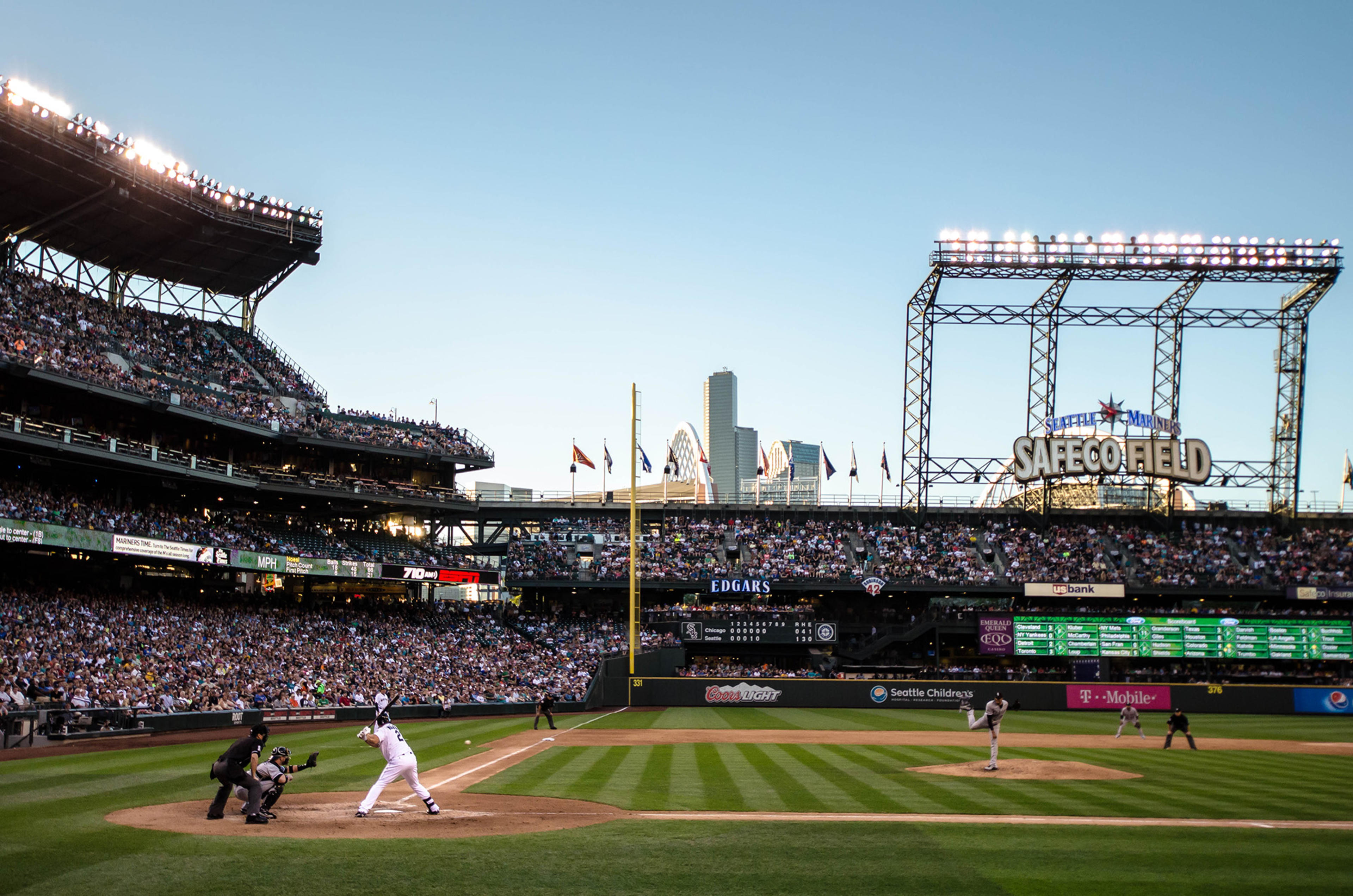 Wide view of Safeco Field during a Seattle Mariners baseball game with packed stands and city skyline in background