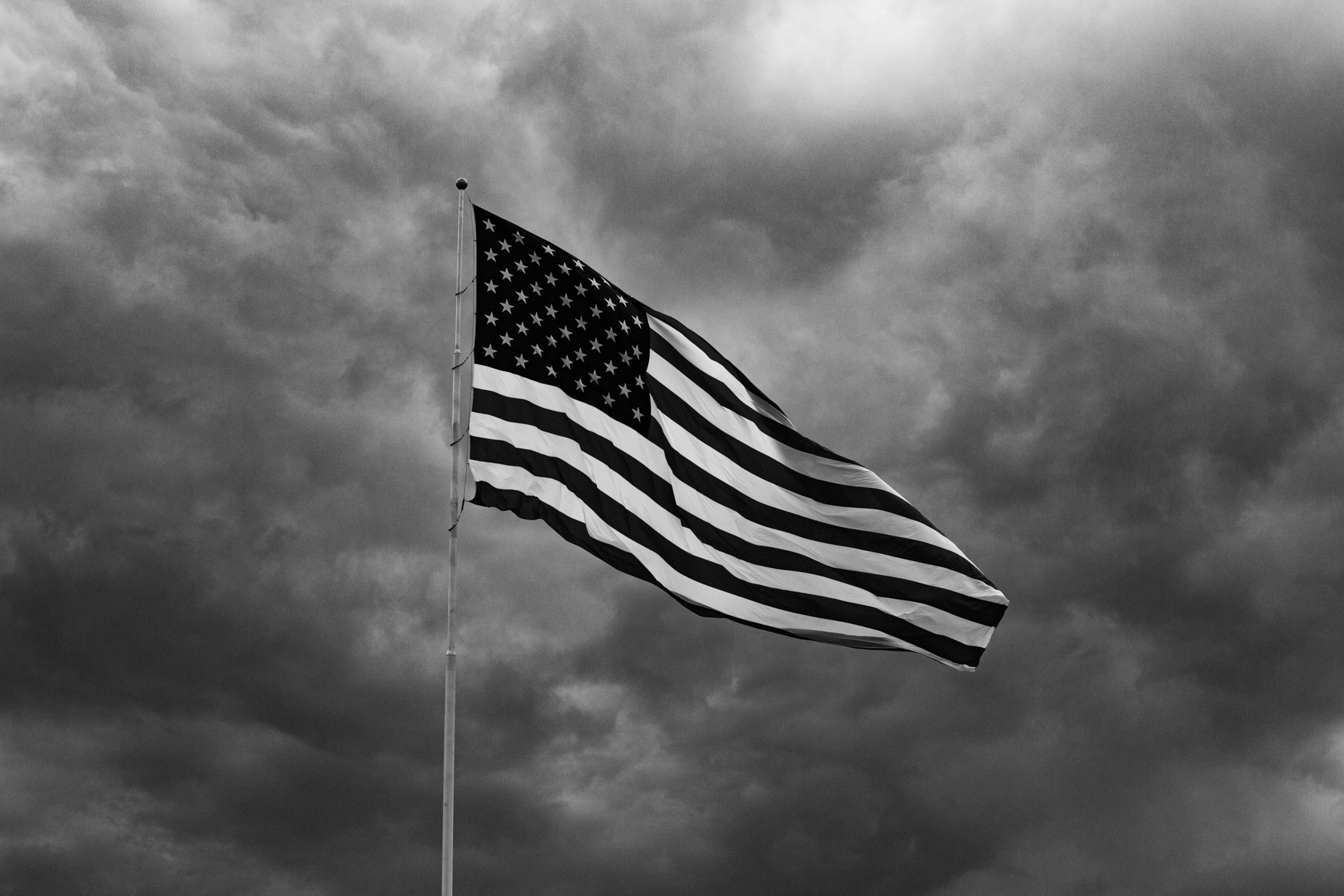 American flag flying against stormy clouds over Arlington National Cemetery
