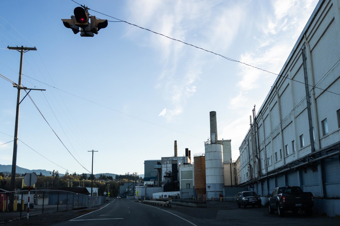 Warning light suspended over mill road with industrial complex in background