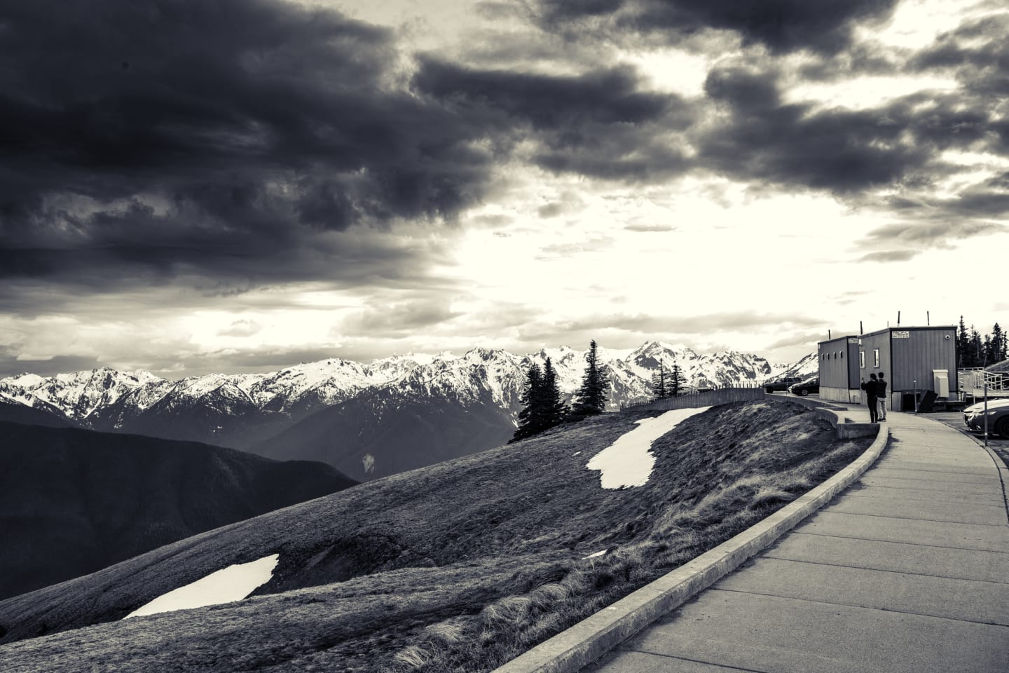 Concrete walkway and observation building on Hurricane Ridge with snow-capped Olympic Mountains in background