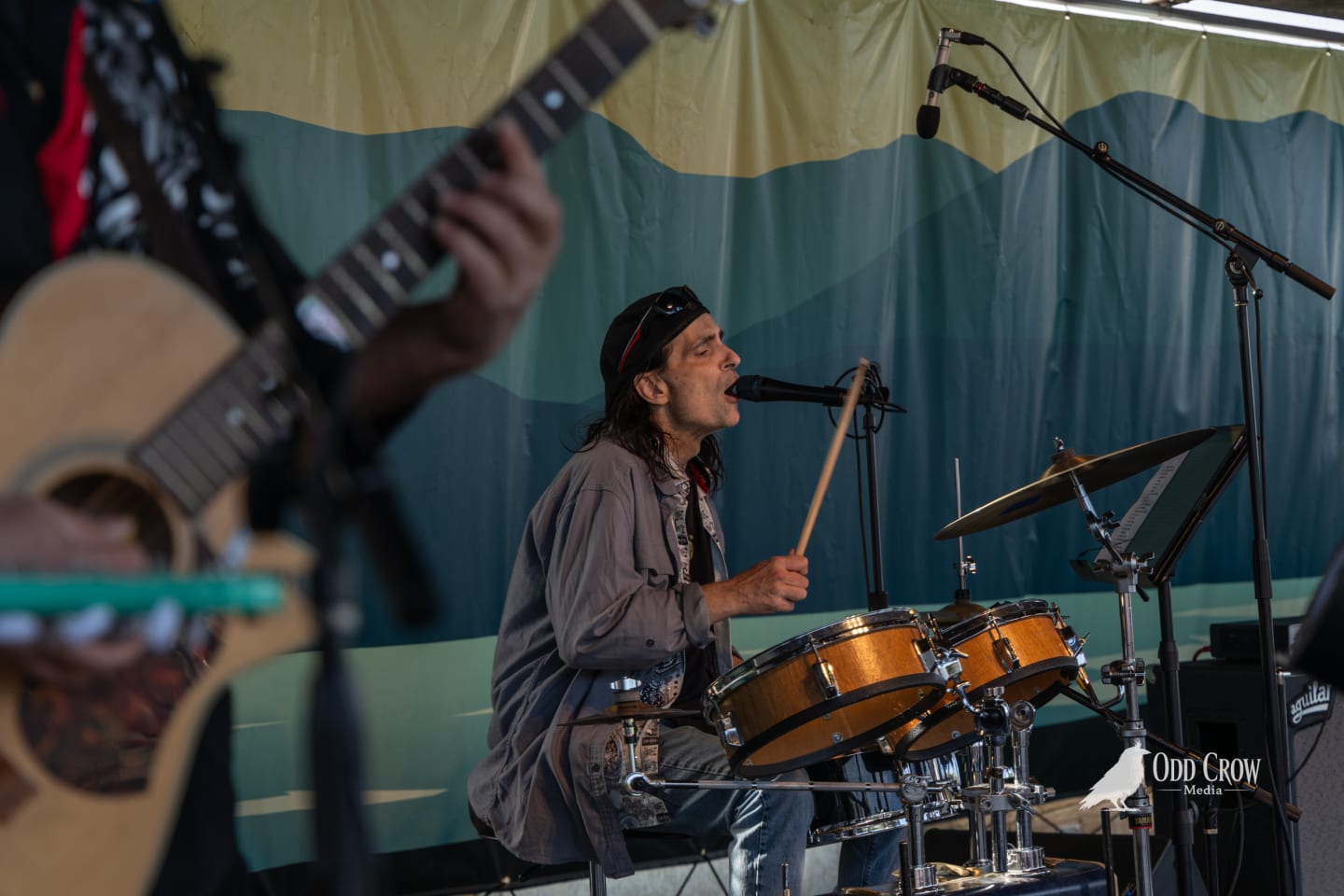 Close-up of the Foot Stompers guitarist's hands playing an acoustic guitar with a tortoiseshell pickguard at Concerts on the Pier
