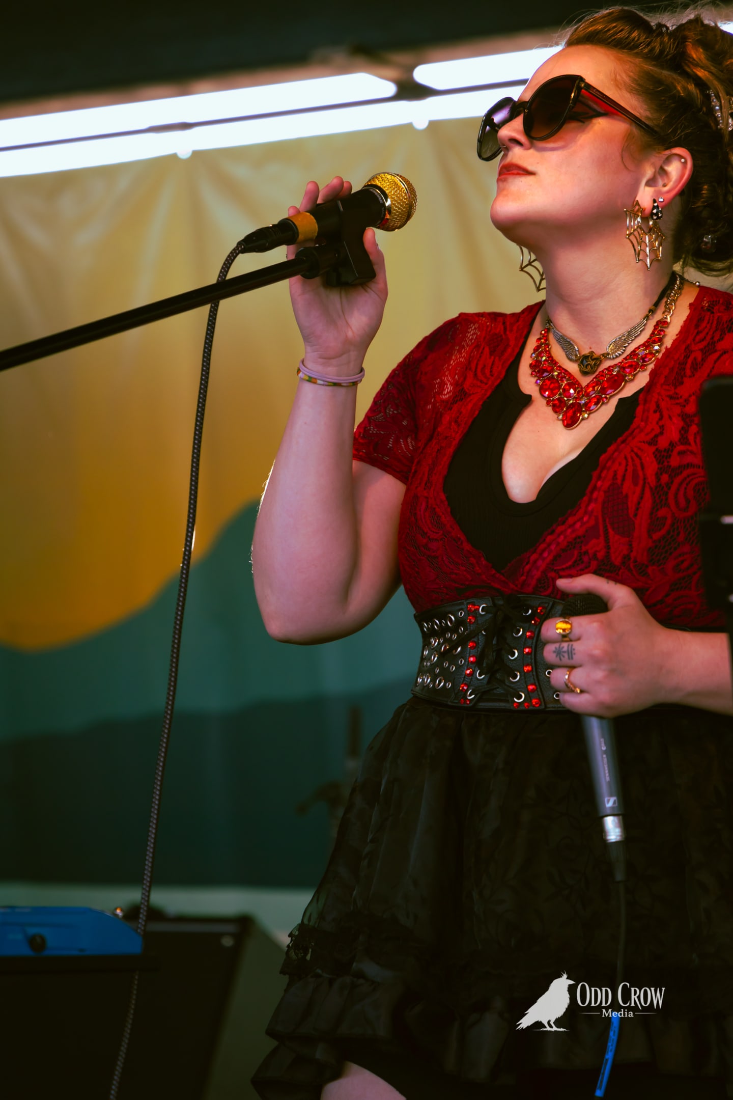 Bee Smith singing with her full red lace outfit and studded belt in view