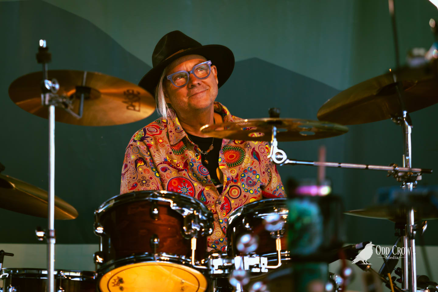 Reckless Dove drummer Craiger Robinson behind the kit in a black hat and patterned shirt on the Port Angeles pier stage