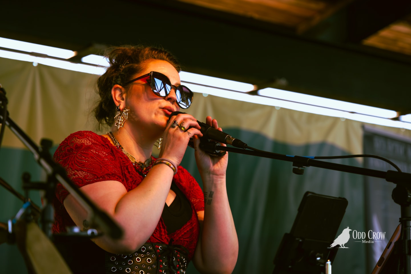 Bee Smith singing in profile, spider-web earrings catching the stage light