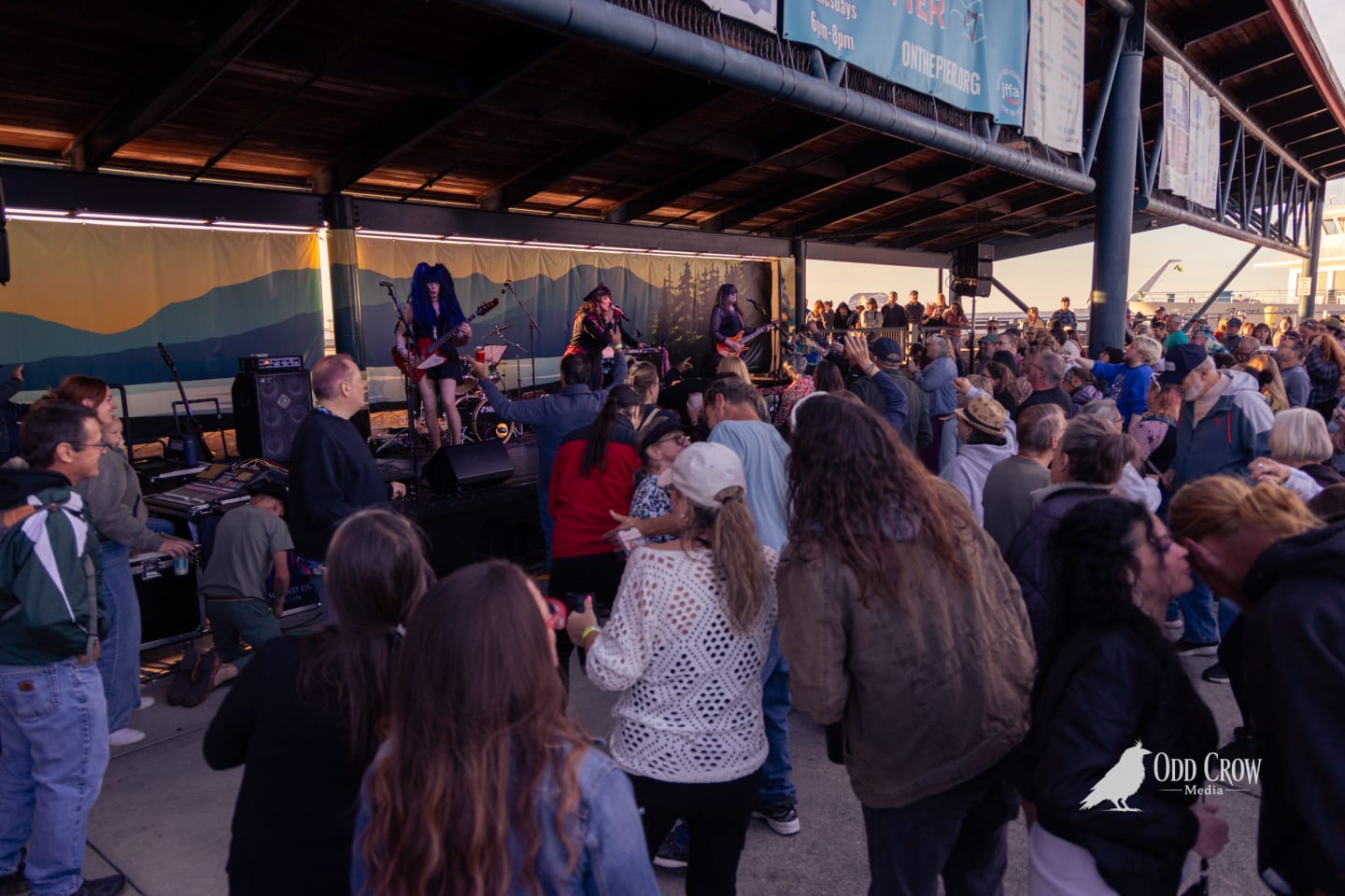 Crowd fills a pier venue as The Nasty Habits perform on stage at golden hour.