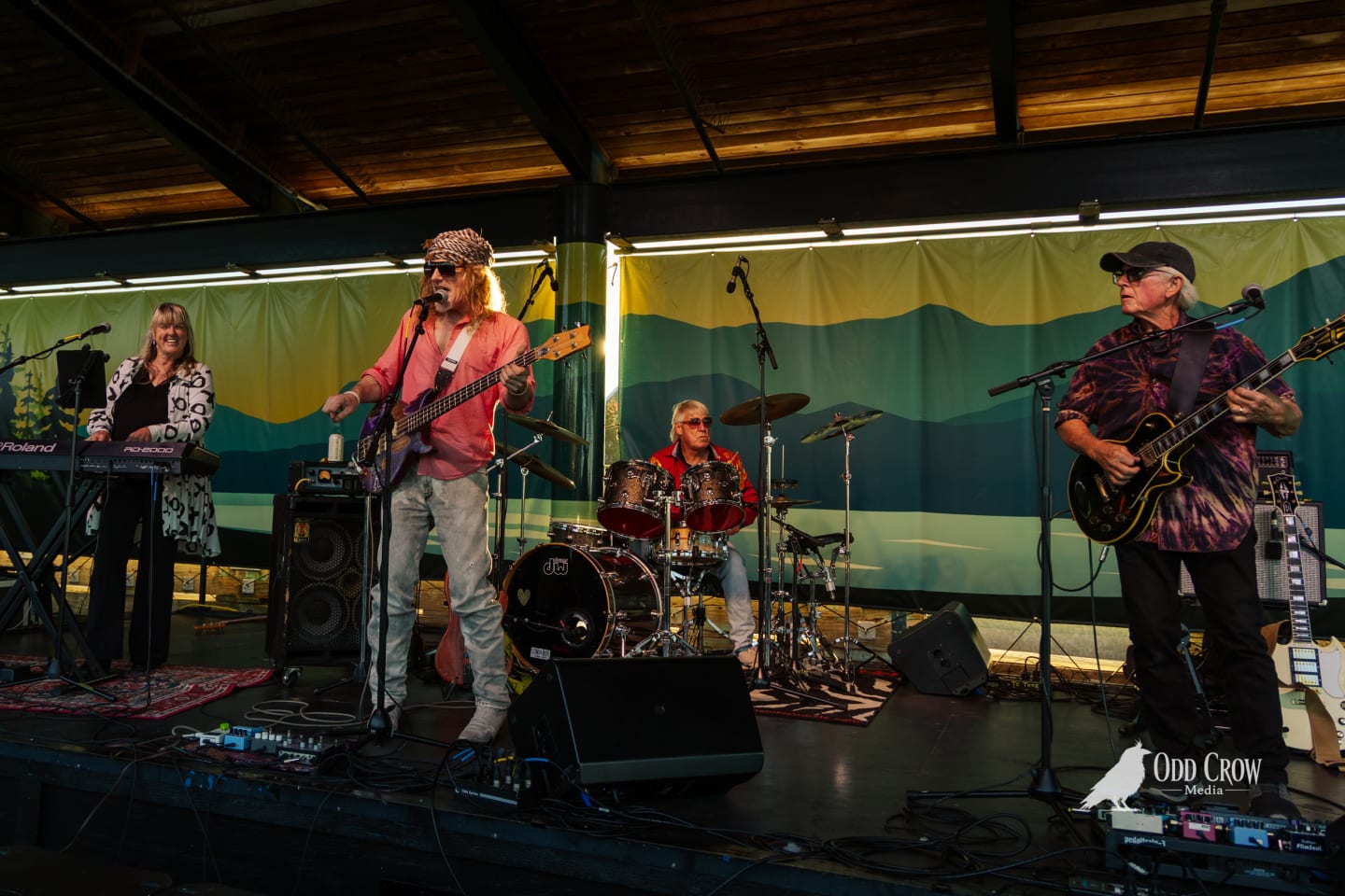 Four-piece band Sound Advice performs on an outdoor covered stage with colorful mountain mural backdrop.