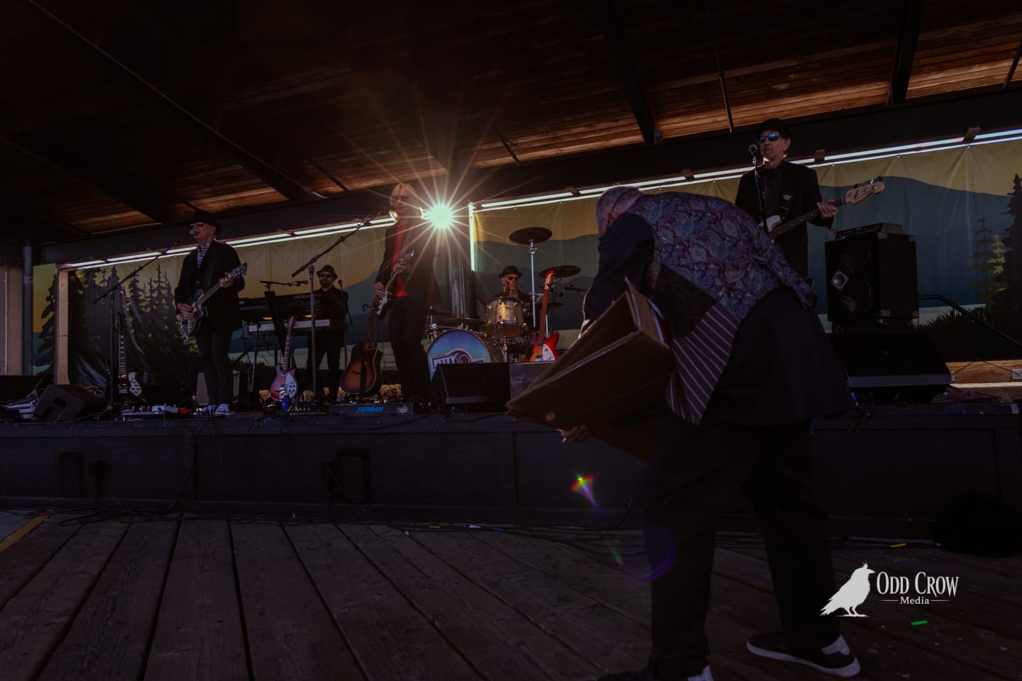 Full stage shot of Petty Fever with crowd dancing right in front of the stage at the Port Angeles pier, Olympic Mountains and town visible in the clear-sky background