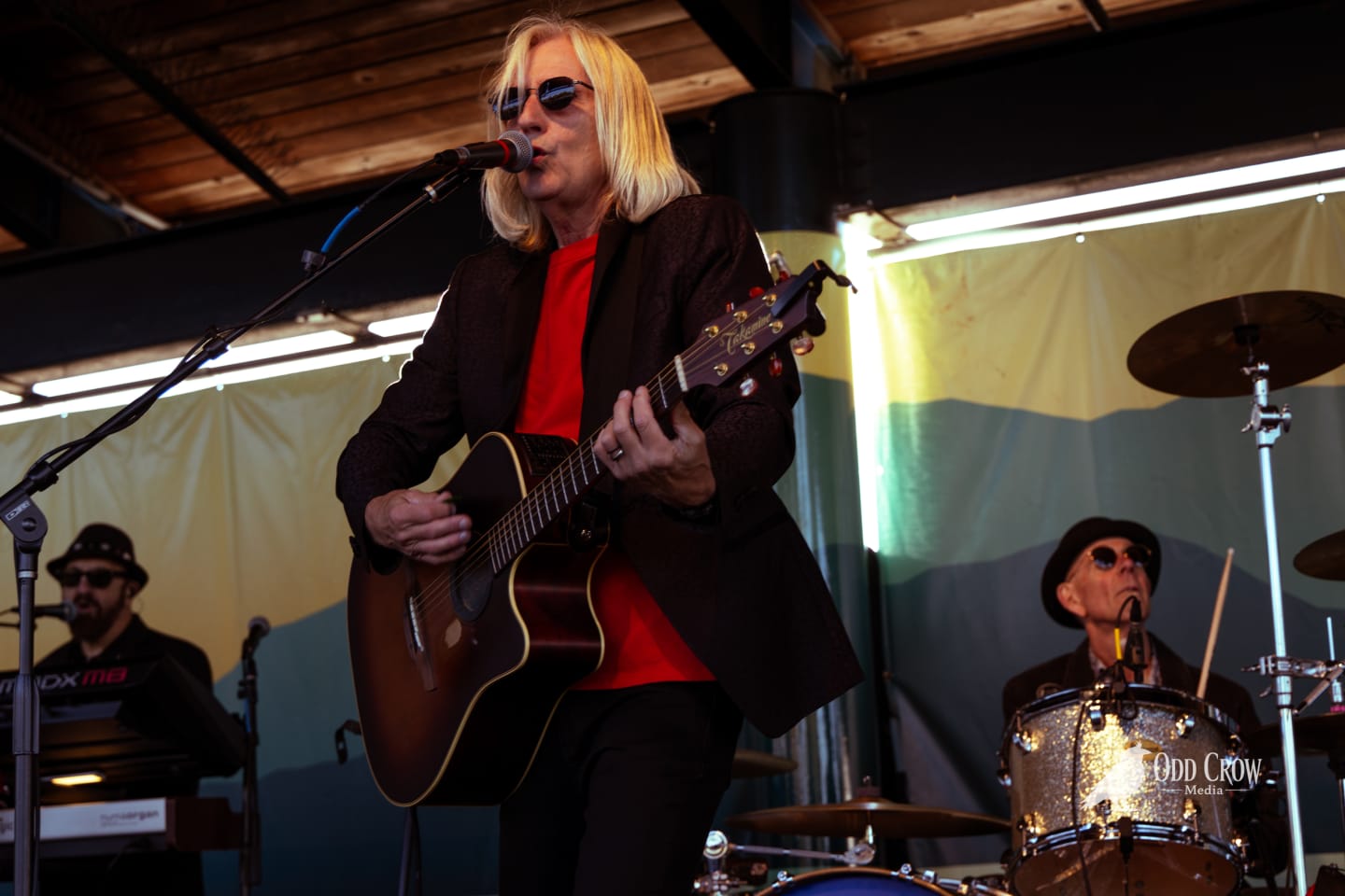Petty Fever full band on stage with all members visible — singer, two guitarists, bassist, drummer, and keyboardist — clean stage shot with mural backdrop