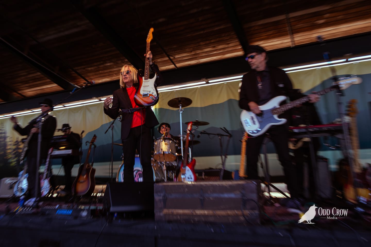Petty Fever singer in red shirt playing cherry sunburst Rickenbacker guitar, smiling and relaxed, Petty Fever Fender amp visible behind him