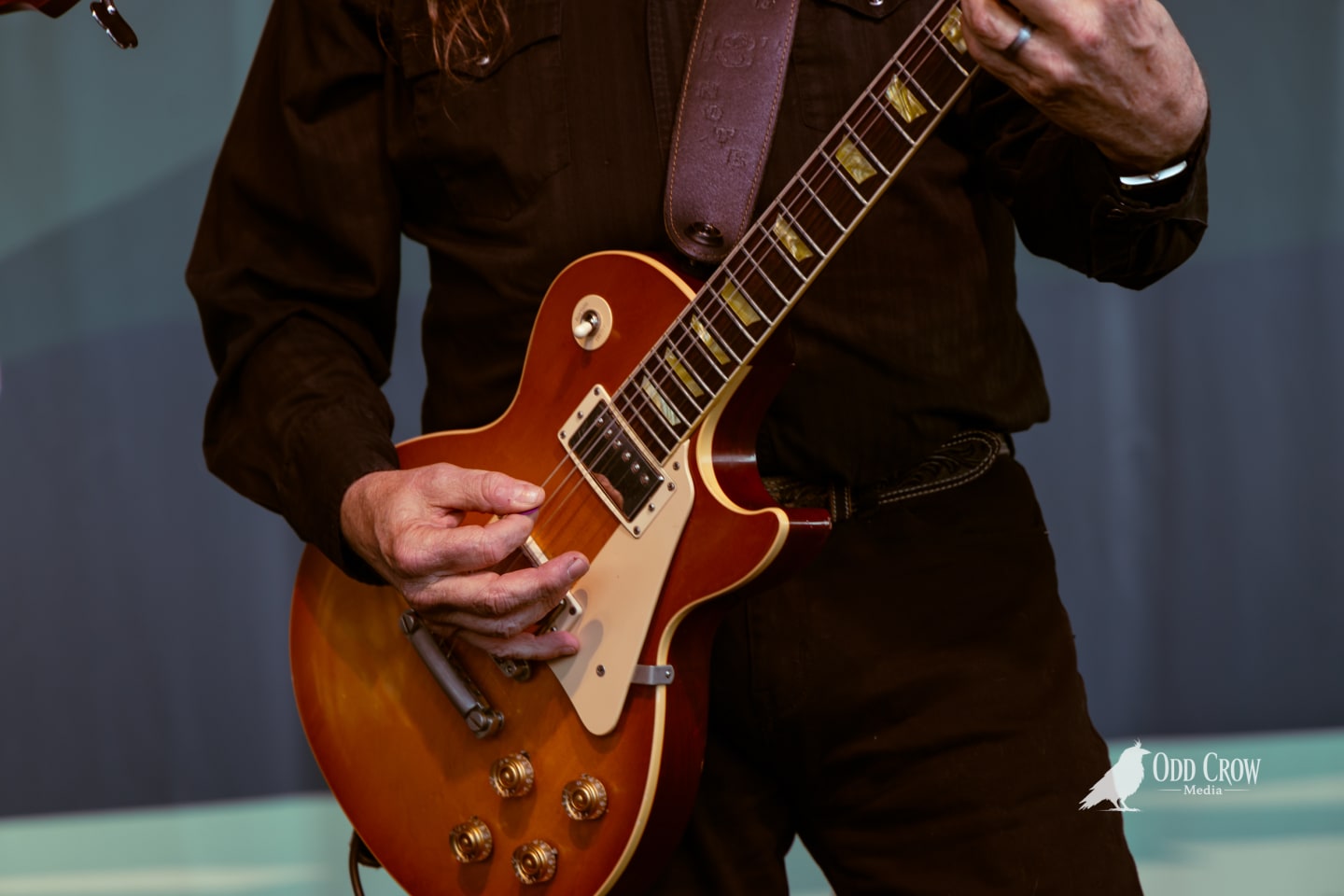 Guitarist playing a sunburst Gibson Les Paul on stage at an outdoor summer concert.