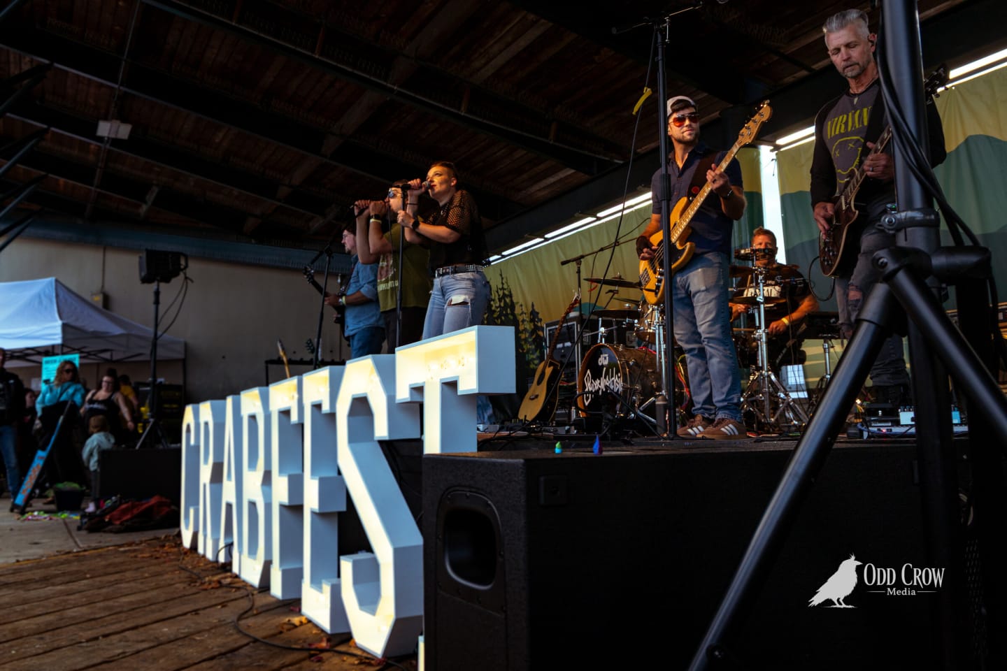 CRABFEST marquee letters in the foreground with the band playing behind them in the evening light