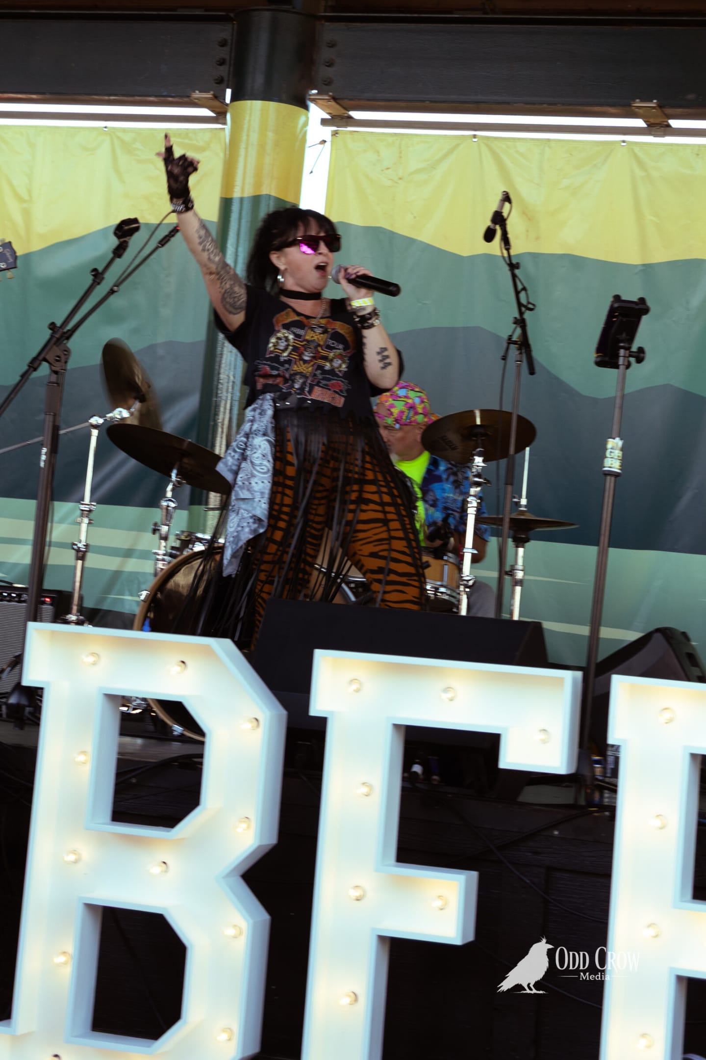 Vocalist with an arm raised on stage behind the lit CRABFEST marquee letters