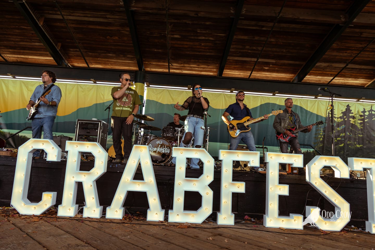 Wide shot of the band on stage behind the lit CRABFEST marquee letters