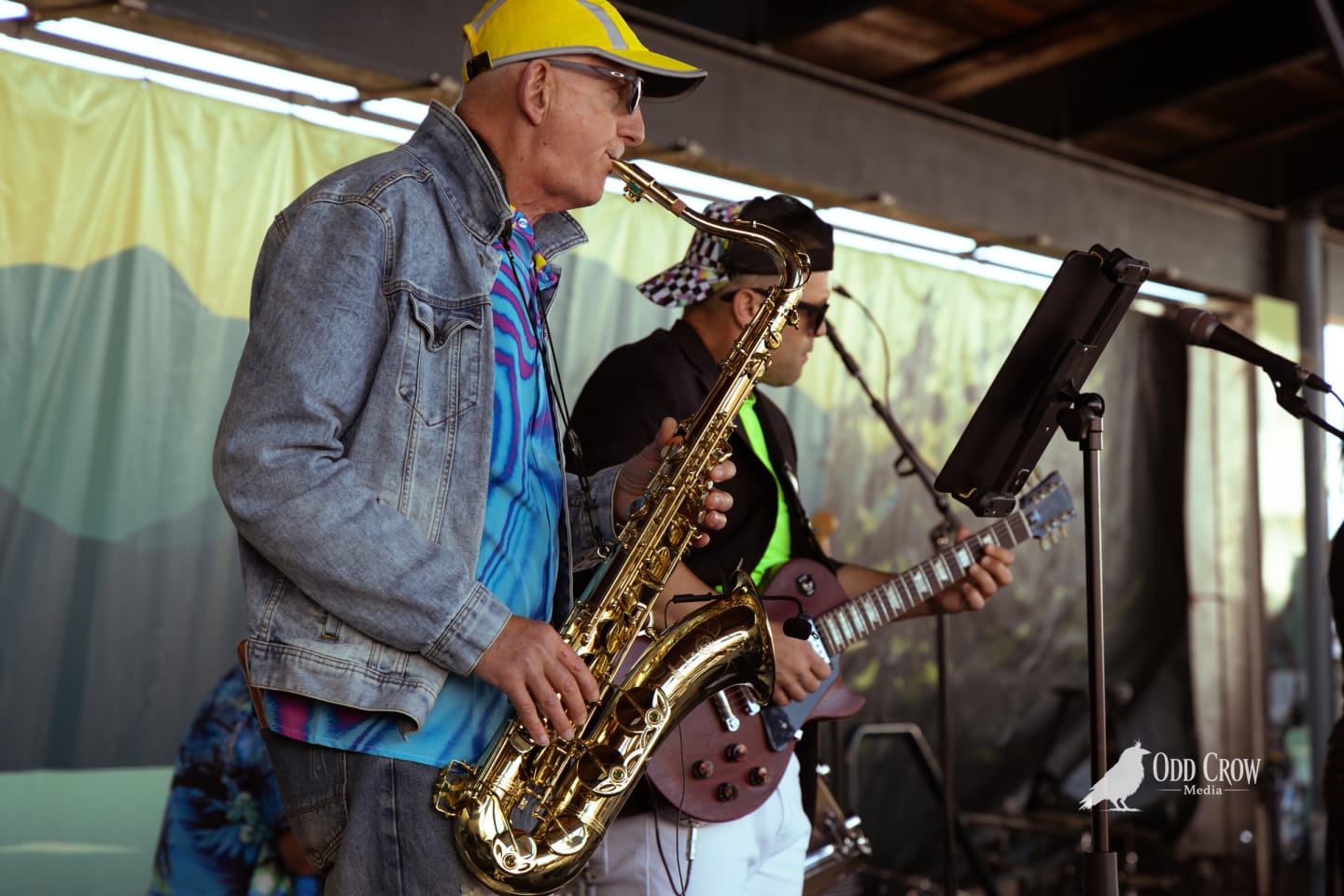 Saxophone player in a yellow cap and denim jacket mid-solo