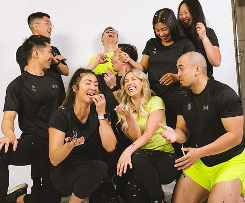 A group of practitioners smiling and looking at each other, sharing a light and happy moment together.
