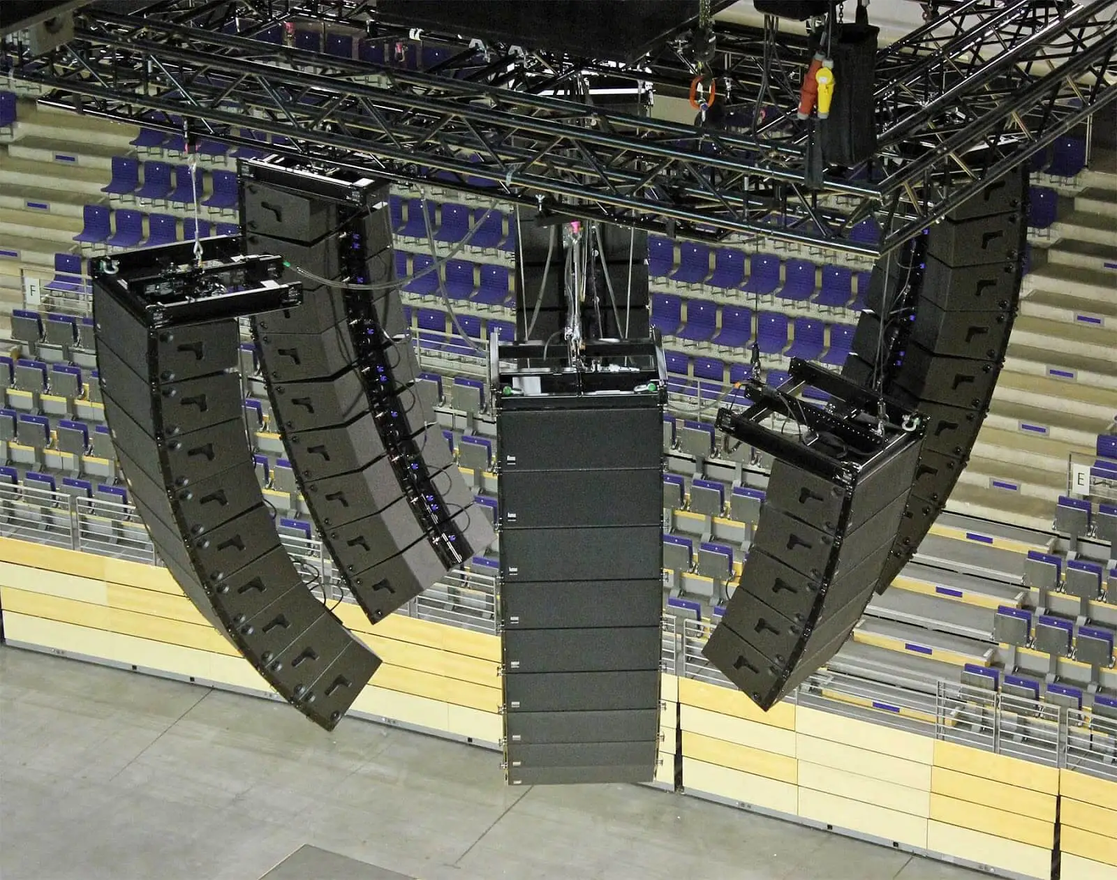 Varios line arrays colgando bajo un truss en un estadio