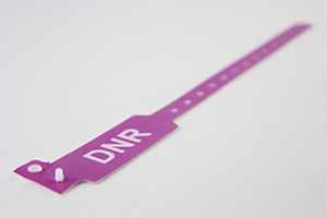 Purple patient wristband for hospital admission with sizing holes, snap closures, and "DNR" in large white text.