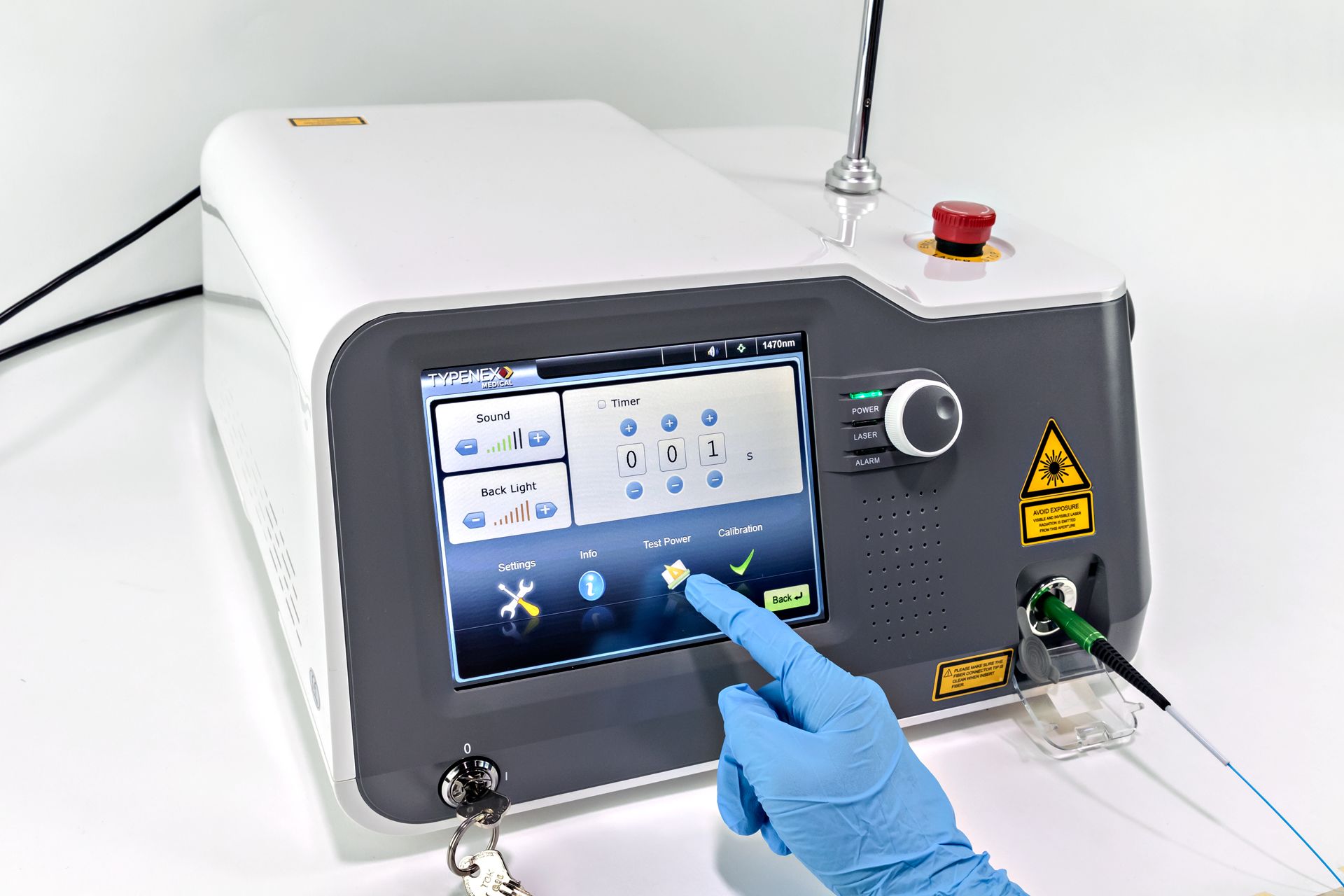 Gloved hand pointing to Test Power on colored touch screen display on Typenex Medical Fibernex FN II Laser System generator.