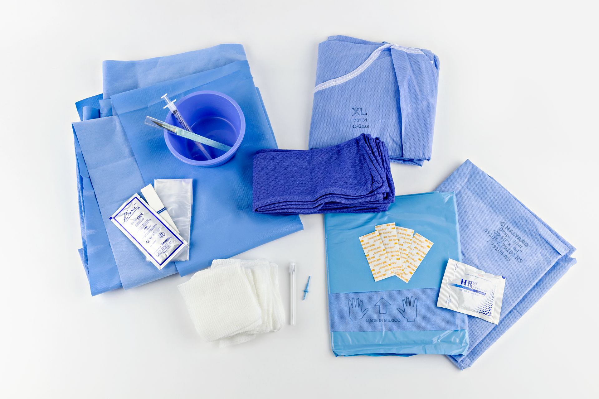 Parts of Typenex Medical Surgical Trays, scattered. XL surgical gown, blue drape sheet, blue towels, syringes, blade scalpel.