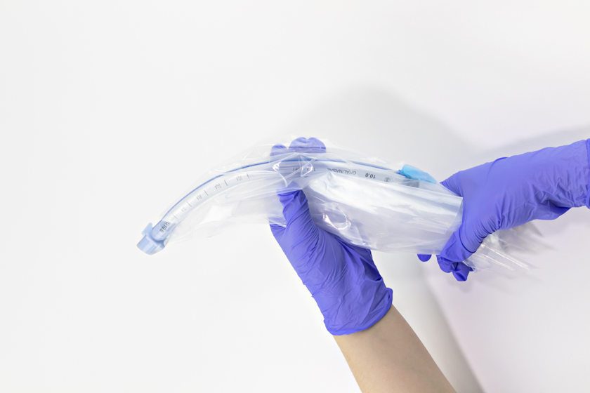 Gloved hands wrapping anesthesia tubing for disposal in Typenex Medical's clear, disposable Extubation Bib.