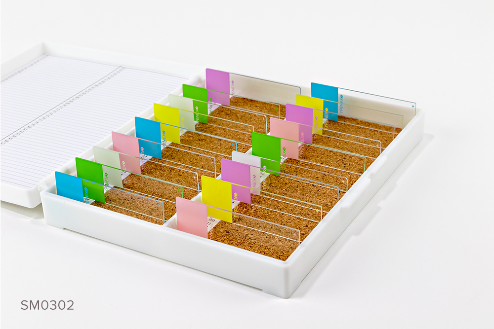 White plastic microscope slide storage box with corked bottom containing assorted color-coded microscope slides. Numerical index up to 100.