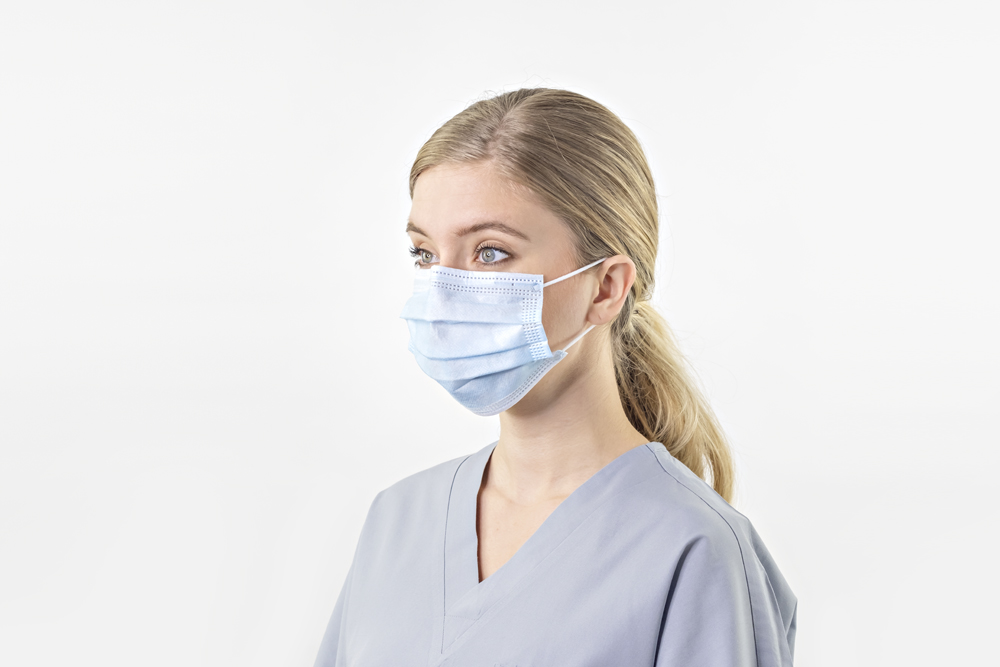 Typenex Medical PPE. Person wearing blue disposable 3-ply medical surgical face mask with ear loops.