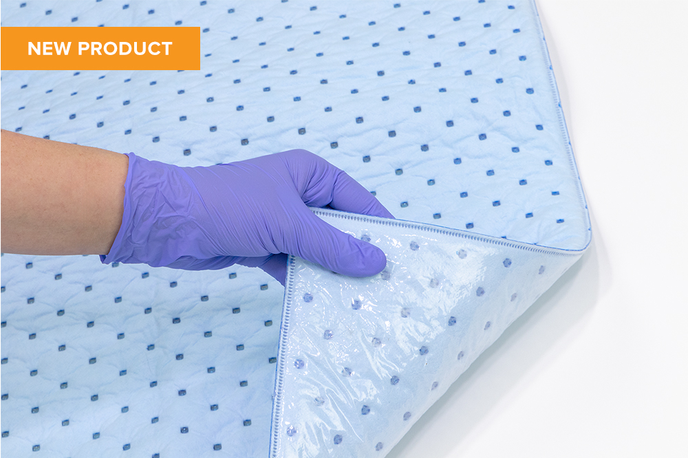 Gloved hand lifting up a corner of the Floor Buddy Absorbent Suction Mat, showing non-slip waterproof backsheet underside.