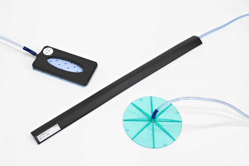 Typenex Medical’s fluid waste management products arranged on the floor: Big Foot Quiet Suction Disc, Fluid Fighter Suction Strip, and Fluid Fighter Suction Disc.