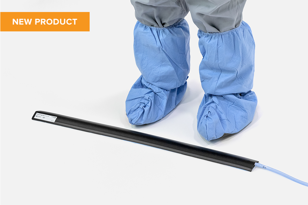 Feet with surgical shoe covers standing next to a Fluid Fighter Suction Strip floor fluid waste barrier. (FM0701)